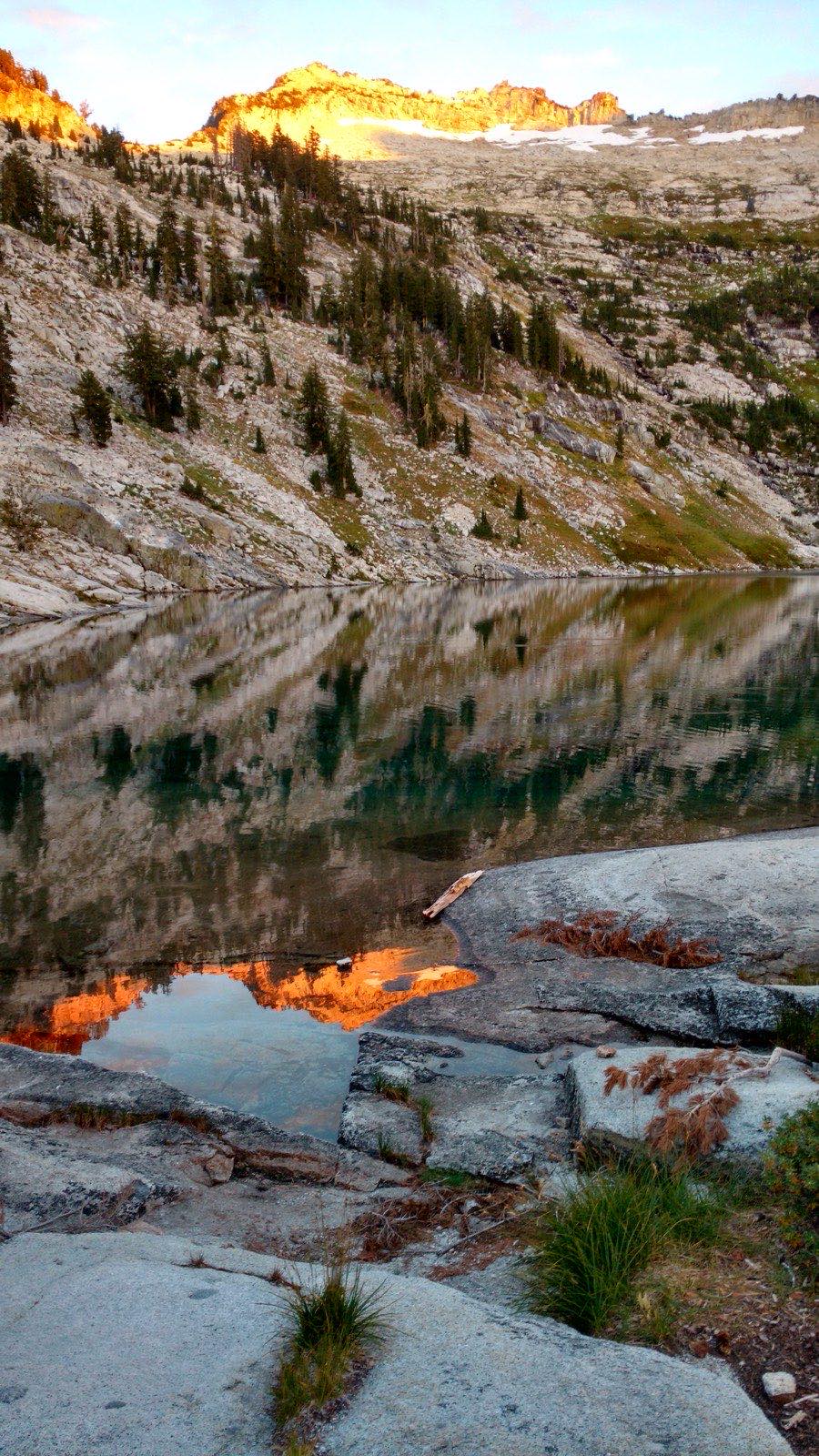 Sunset alpenglow lighting granite peaks above Grizzly Lake in the Trinity Alps Wilderness, the orange ridge reflected in still water