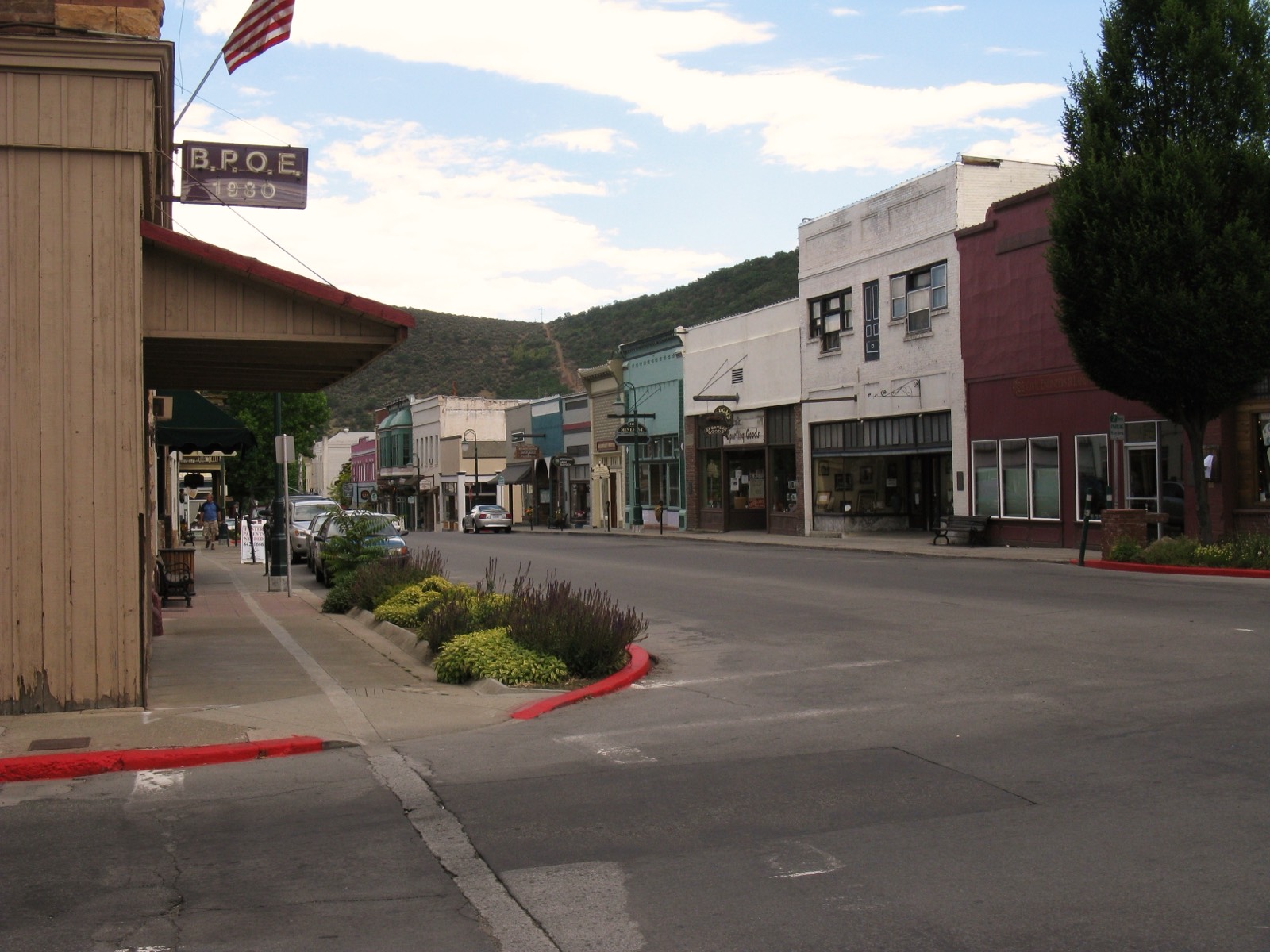 Historic West Miner Street in downtown Yreka with early-1900s brick and wood storefronts, an Elks lodge sign, and a hillside at the end of the street